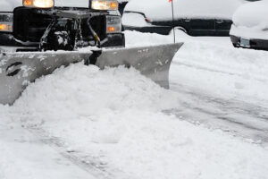 A commercial plow removing snow from a business parking lot in Springfield, IL thanks to expert snow removal services.