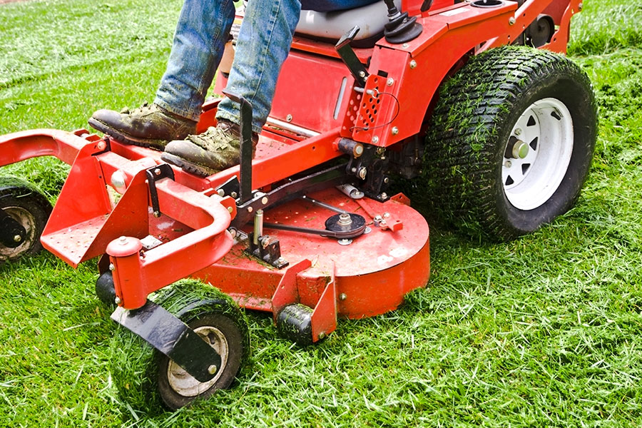 A professional landscaping expert using a commercial riding lawn mower to cut the lawn of a business in Springfield, IL for seasonal landscaping.