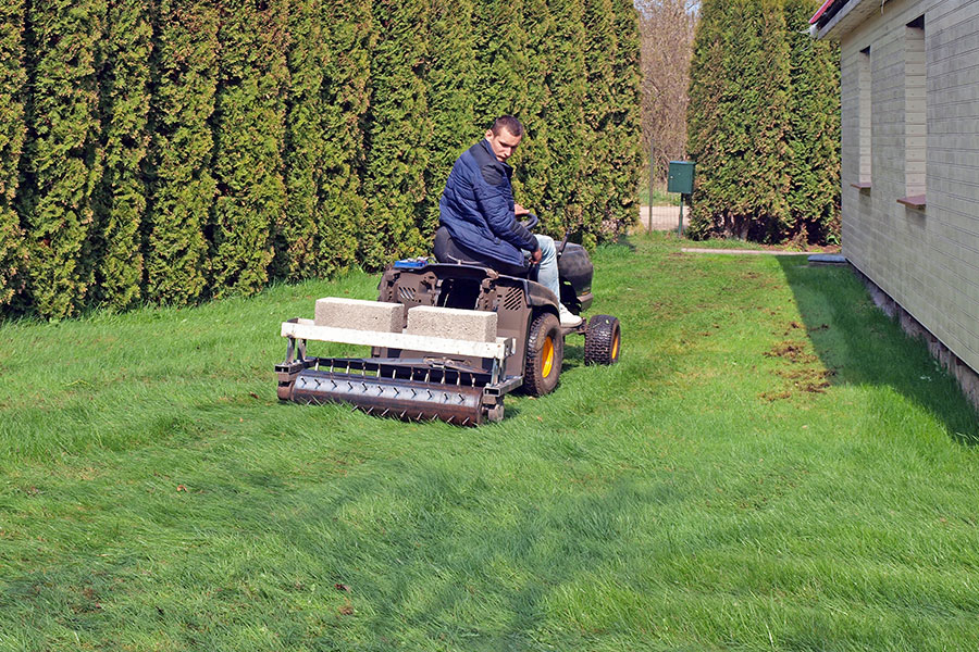 A professional landscaping expert using an aeration machine to help a residential lawn access oxygen, water, and nutrients in the soil in Springfield, IL.